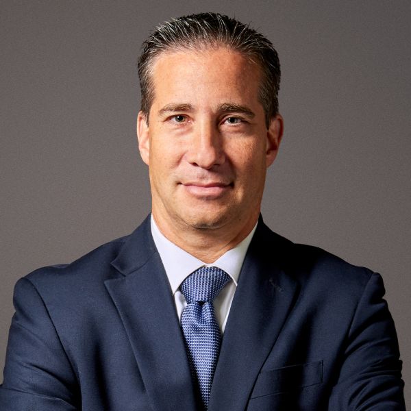 Professional man in a suit and tie with a confident expression, posing against a neutral background.