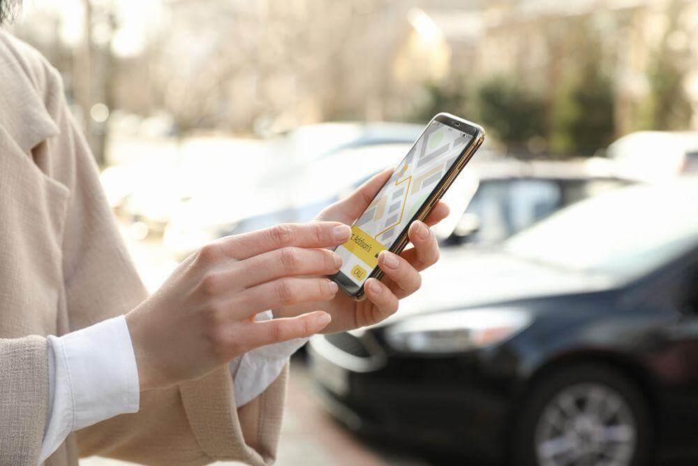 Woman holding smartphone, likely a client reviewing a rides