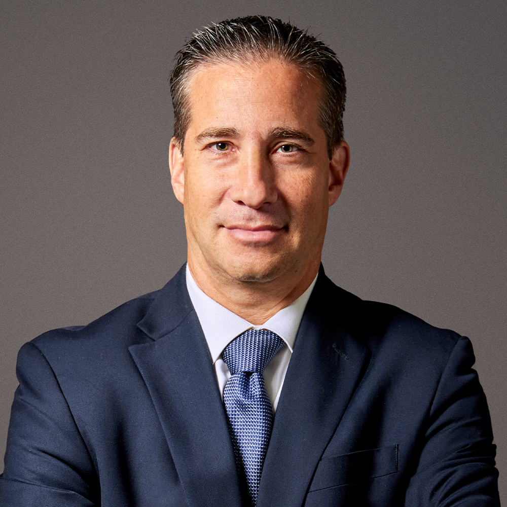 Professional man in a suit and tie with a confident expression, posing against a neutral background.